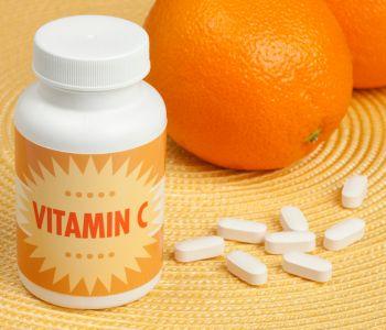 Bottle of Vitamin C Tablets Next to 2 Oranges